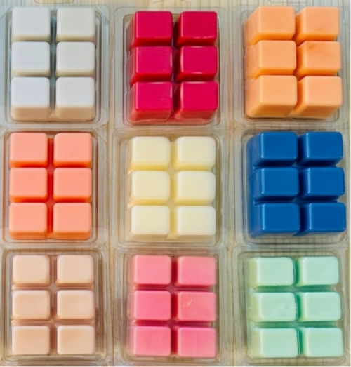 Twelve wax melts in assorted pastel and bright colors, arranged in a neat 3x4 grid inside clear plastic clamshell packaging.